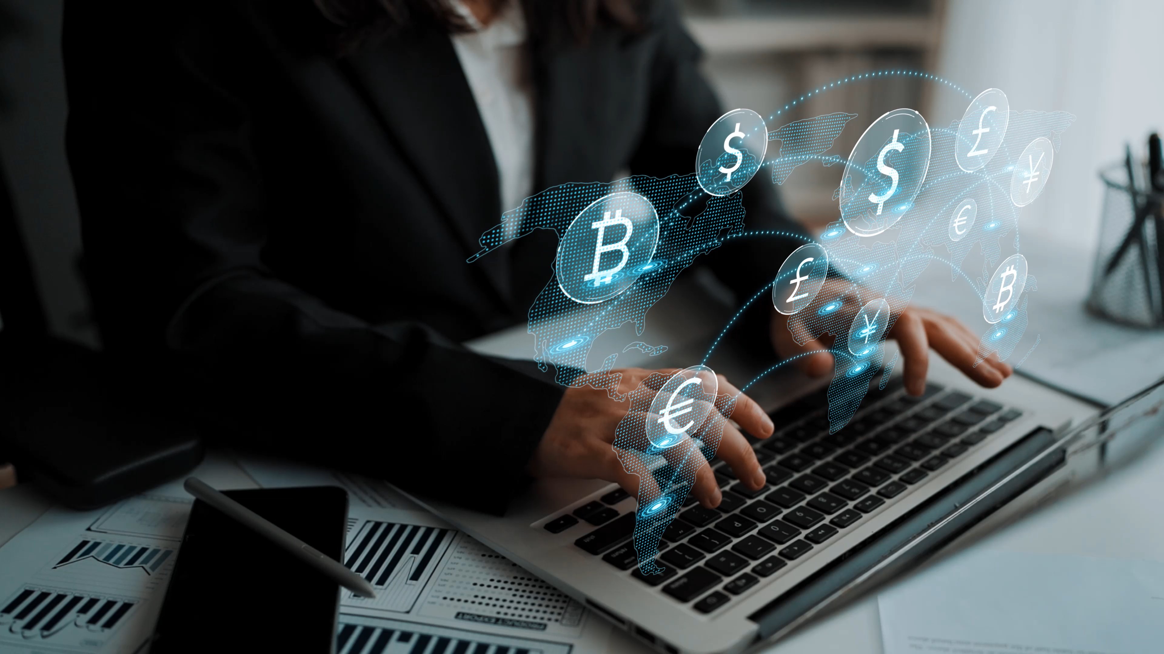 A business professional types on a laptop while various virtual currency icons hover above, illustrating the dynamic world of finance and digital transactions in a modern office setting.