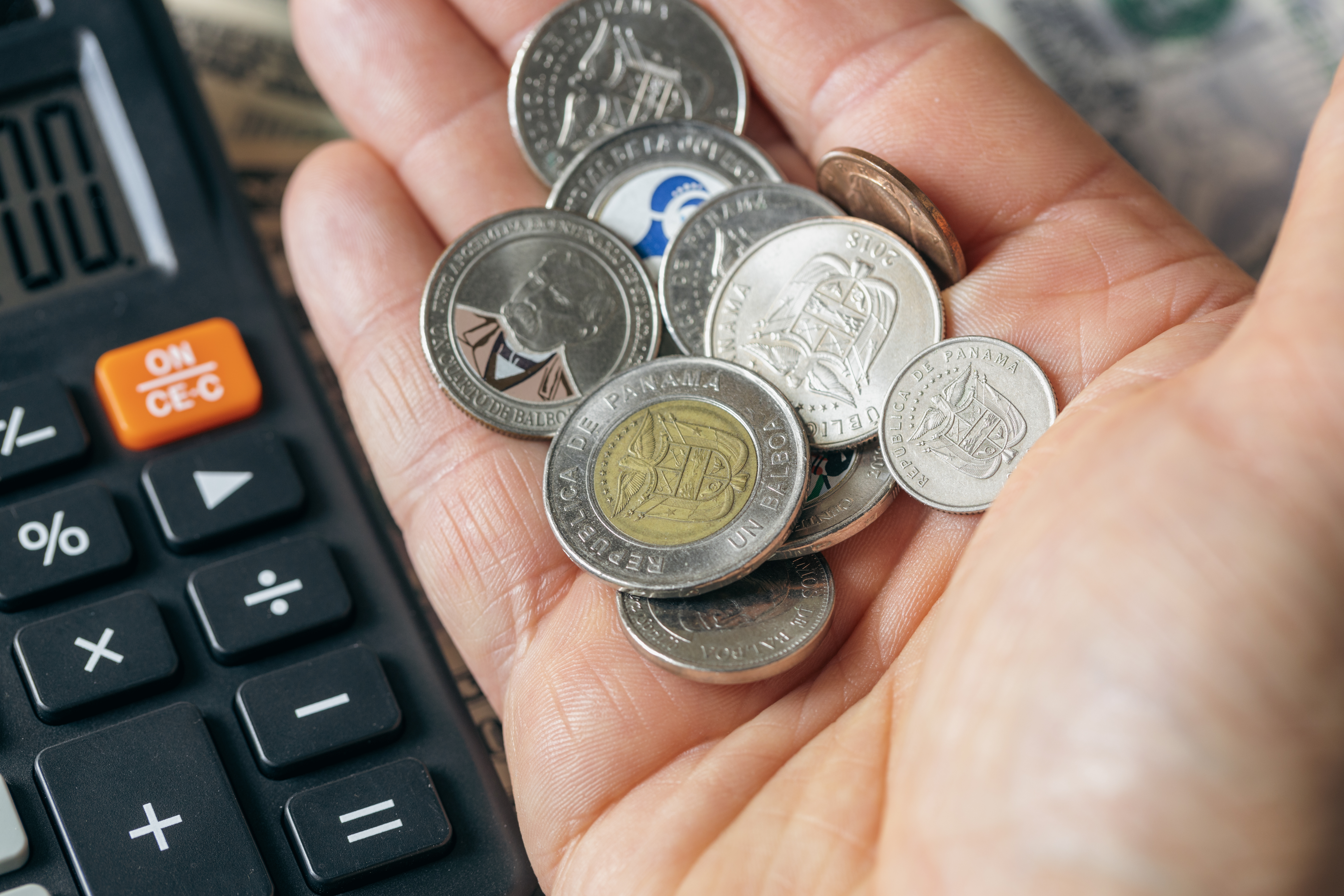 Panama money and calculator, close up of Panamanian balboa coins held in hand, financial and business concept.