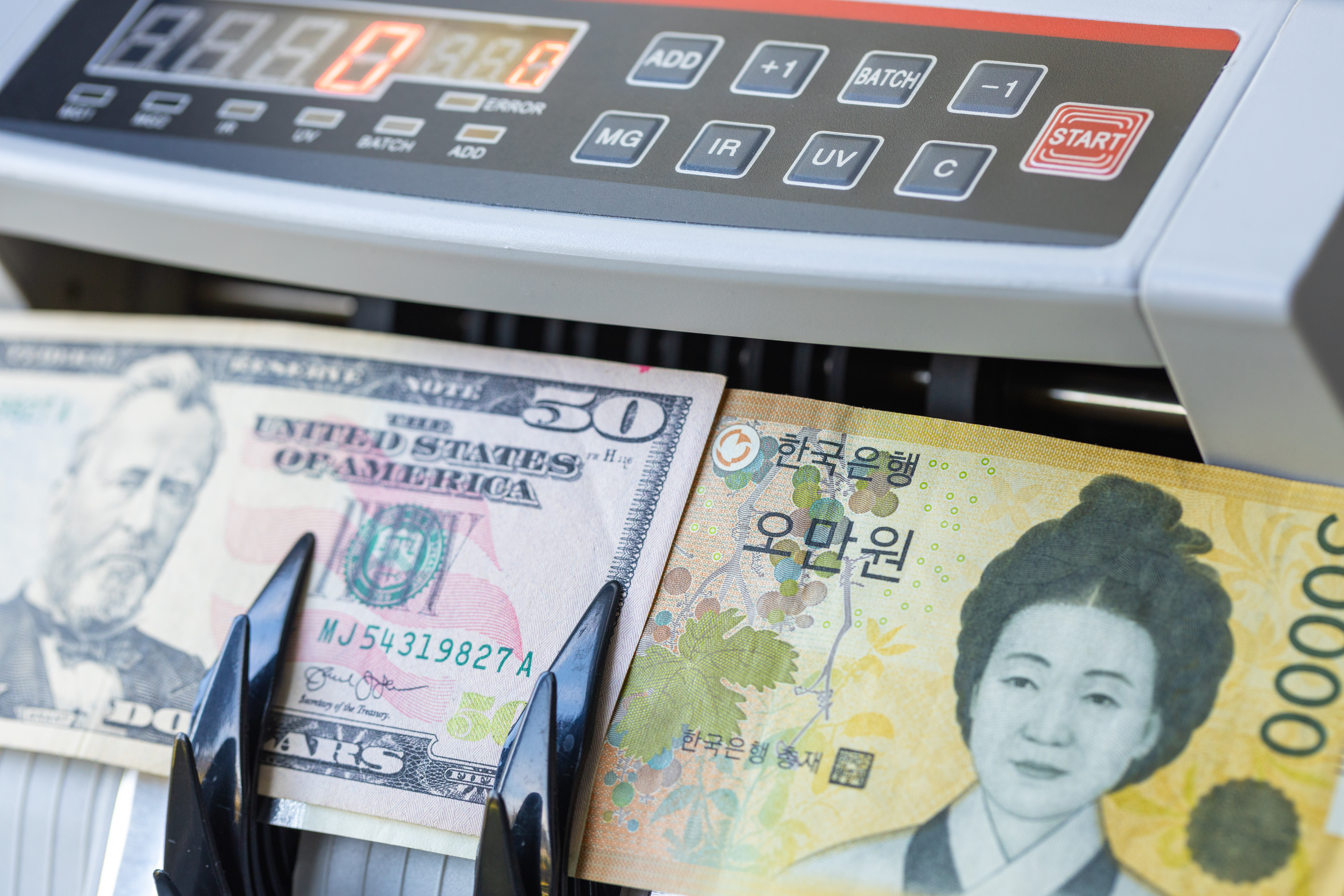 USD and KRW banknotes inside counting machine. Economic concept of South Korean won and US dollar exchange rate, forex trading, asian market finance and global valuation. Close up.